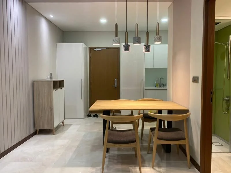Dining features: wooden dining table, 4 dining chairs, pendant lighting with 3 fixtures, cream painted walls, tile flooring, built-in cabinetry, white refrigerator, kitchen area visible in background; style: modern.