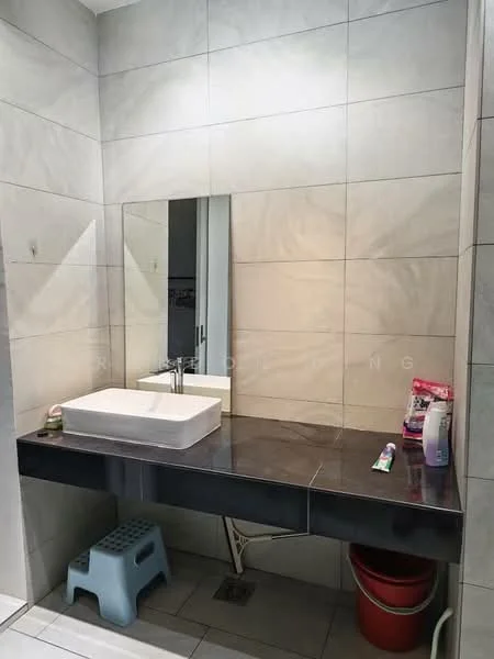 Bathroom features: grey tiled walls, white ceramic sink, black countertop, mirror above sink, wall-mounted faucet, floor drain, blue plastic stool, red bucket, toothpaste, liquid soap dispenser, cleaning supplies; style: modern.