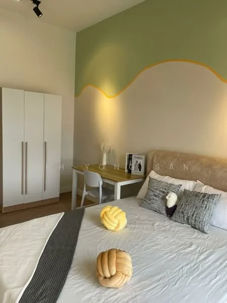 Bedroom features: queen-size bed with upholstered headboard, decorative pillows, white bedding, light wood flooring, green and beige accent wall, two wall-mounted lights, white wardrobe with two doors, small study desk with chair, framed artwork on desk, decorative plant on desk; style: modern.