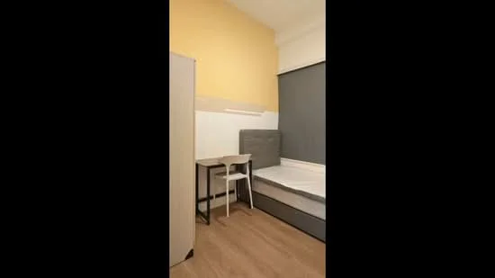 Bedroom features: yellow painted walls, grey upholstered headboard, single bed, wooden flooring, desk with metal legs, white chair, built-in wardrobe, window with roller blinds; style: modern.