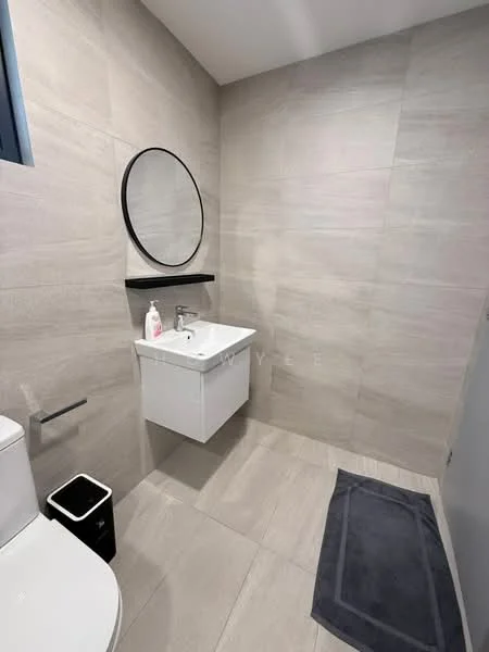 Bathroom features: grey tile flooring, light grey wall tiles, white wall-mounted vanity, single-sink vanity, chrome basin mixer faucet, round black-framed mirror, black wall shelf, toilet, black trash bin, dark grey bath mat, window with black frame; style: modern.