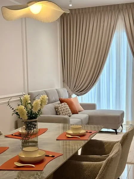 Living features: light grey fabric sofa, orange accent pillows, glass coffee table, cream curtains, floor-to-ceiling windows, recessed ceiling lights, decorative vase with flowers, dining table with place settings; style: modern.