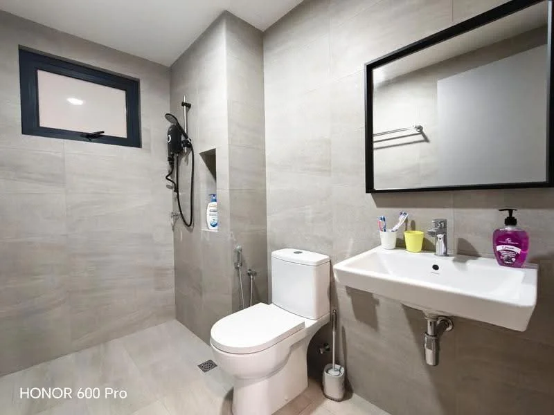 Bathroom features: grey tile flooring, light grey wall tiles, white wall-mounted sink, chrome basin mixer faucet, framed mirror, one-piece toilet, shower area with glass partition, handheld shower, wall-mounted showerhead, towel rack, small window, soap dispenser; style: modern.