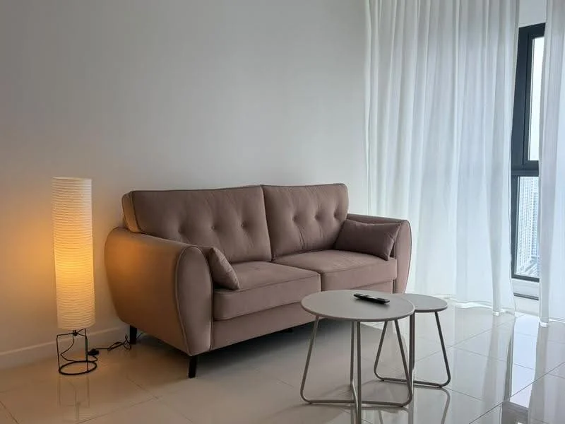 Living features: 3-seater fabric sofa in light brown, white floor-to-ceiling windows, sheer white curtains, round coffee table with metal legs, floor lamp with a cylindrical shade, glossy white tile flooring, neutral painted walls, city view through window; style: modern; view: city.