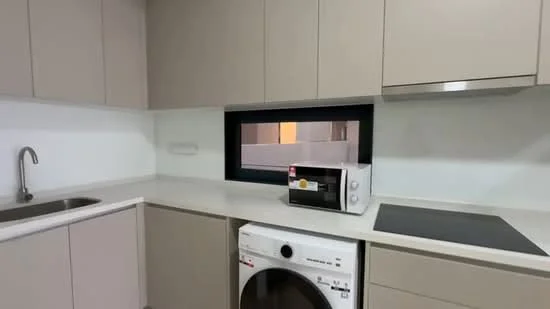 Kitchen features: single-bowl stainless-steel sink, chrome pull-down faucet, white quartz countertop, light beige cabinetry, built-in oven, microwave, front-load washing machine, ceramic tile flooring, window with black frame, recessed downlights; style: modern.