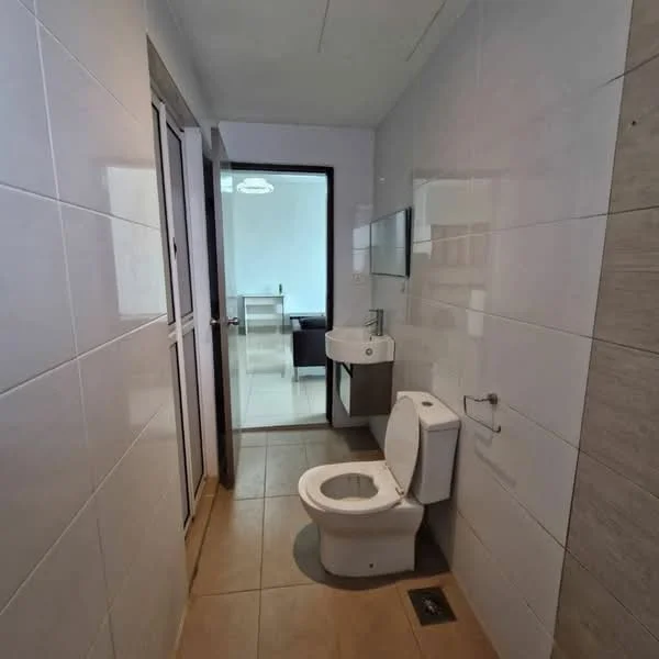 Bathroom features: white tiled walls, light brown tiled flooring, one-piece toilet, wall-mounted sink, mirror above sink, glass shower enclosure, door leading to another room, natural light from adjacent room; style: modern.