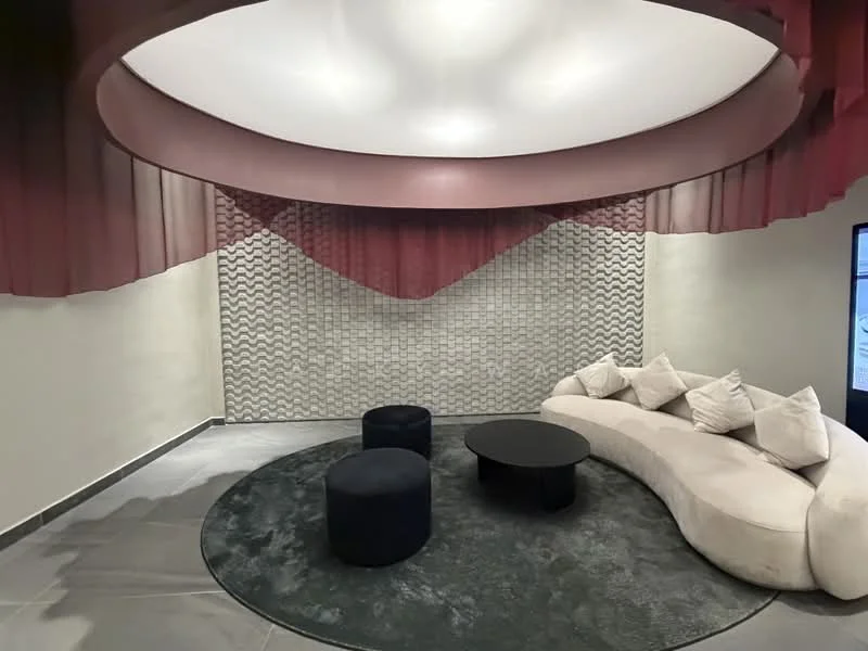 Room features: curved sectional sofa in cream, black round coffee table, two black ottomans, textured wall with wave pattern, recessed ceiling with circular design, soft lighting, grey tile flooring, decorative fabric draping in maroon; style: modern.