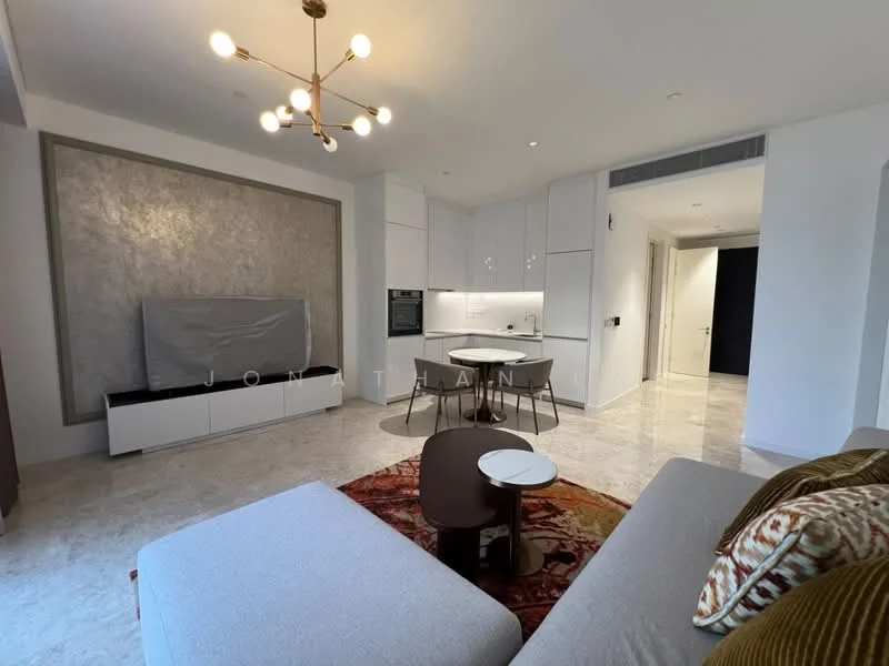 Living features: light grey fabric sofa, decorative cushions, round coffee table, TV console, wall-mounted TV, chandelier with multiple bulbs, marble flooring, white cabinetry, built-in oven, recessed lighting, open-plan layout, neutral wall colour, textured accent wall; style: modern.