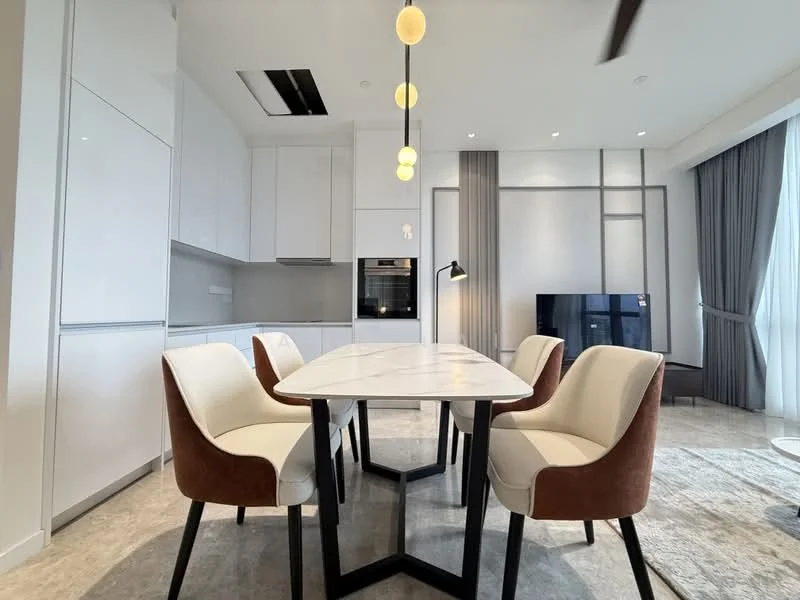 Dining features: 6-seater dining table with marble top, upholstered dining chairs in cream and brown, pendant lighting with round bulbs, floor-to-ceiling windows with sheer curtains, grey area rug, wall-mounted TV, built-in cabinetry in white, recessed ceiling lights, open-plan layout connecting to kitchen, light grey flooring; style: modern; view: city. Kitchen features: white cabinetry, built-in oven, grey backsplash, stainless-steel appliances, countertop with integrated sink, open shelving, recessed lighting; style: modern.