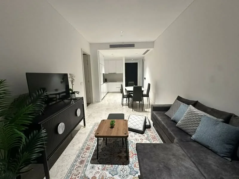 Living features: grey fabric sectional sofa, wood coffee table, TV console with circular speakers, wall-mounted flat-screen TV, area rug with geometric pattern, decorative plant, recessed downlights, white painted walls, marble tile flooring, dining area with black dining table and chairs, open kitchen in background; style: modern.