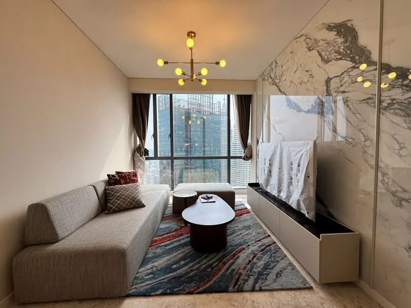 Living features: 3-seater fabric sofa in light grey, round coffee table, area rug with abstract pattern, wall-mounted TV, TV console with storage, large floor-to-ceiling windows, curtains in dark brown, marble accent wall, chandelier with multiple bulbs, decorative cushions, wooden flooring; style: modern; view: city.