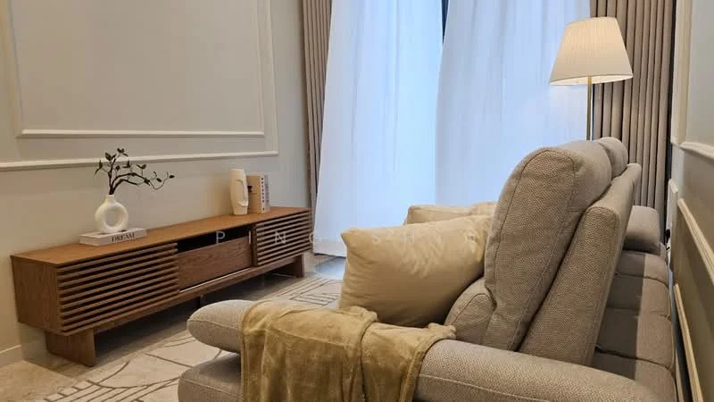 Living features: 3-seater fabric sofa in light grey, decorative throw blanket in beige, two large cushions in cream, wooden TV console with slatted design, decorative vase on console, framed artwork on wall, floor-to-ceiling curtains in light fabric, recessed lighting, area rug with geometric pattern, light-colored stone flooring; style: modern.