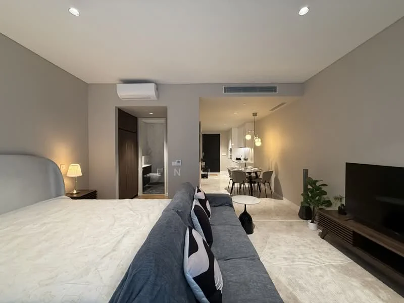 Room features: king-size bed with upholstered headboard, 2 bedside tables, wall-mounted TV, sofa with cushions, carpeted flooring, recessed downlights, wall-mounted air conditioning unit, decorative plant in pot, neutral painted walls, open layout to dining area, dining table with chairs visible in background, kitchen area visible in background; style: modern.
