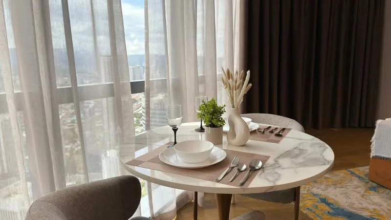 Dining features: round marble dining table, upholstered dining chairs in grey, table setting with plates and cutlery, decorative vase with dried flowers, small potted plant, sheer curtains, floor-to-ceiling windows, wooden flooring; style: modern; view: city.