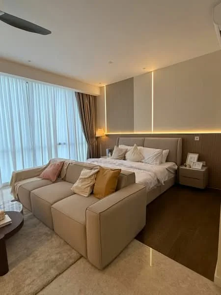 Bedroom features: king-size bed with upholstered headboard, white bedding with decorative pillows, 2 bedside lamps, floor-to-ceiling windows with sheer curtains, wooden flooring, beige fabric sofa, coffee table, decorative throw pillows, accent wall with LED lighting, carpeted area rug; style: modern.