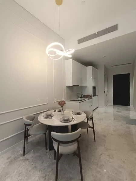 Dining features: round dining table, 4 upholstered dining chairs, white marble flooring, white painted walls, modern pendant light fixture, built-in kitchen cabinetry, stainless-steel appliances, black countertop, open layout, decorative vase on table; style: modern. Kitchen features: built-in kitchen cabinetry, stainless-steel fridge, stainless-steel oven, black countertop; style: modern. Hallway features: white painted walls, marble flooring, black door, recessed lighting; style: modern.