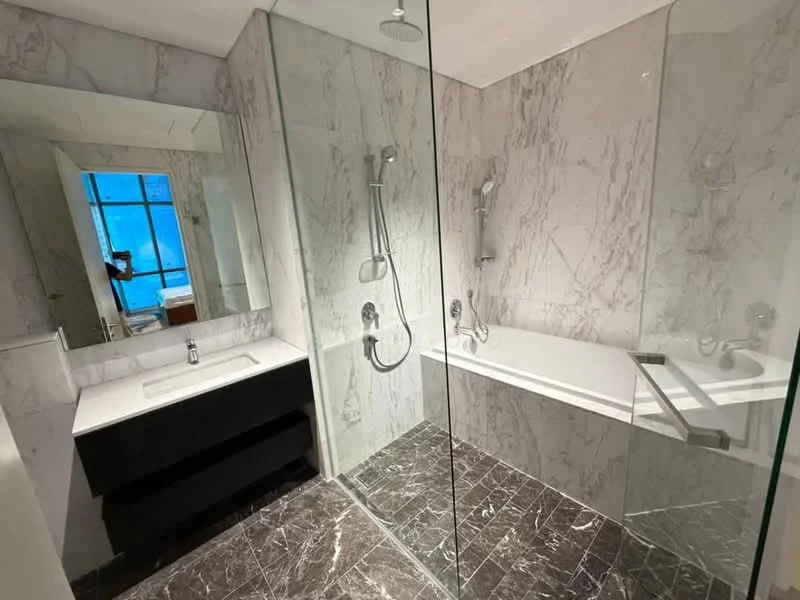 Bathroom features: marble tile walls, glass shower enclosure, freestanding bathtub, dual shower heads, single-sink vanity with black cabinetry, mirror above vanity, chrome faucets, dark stone flooring, recessed lighting; style: modern.