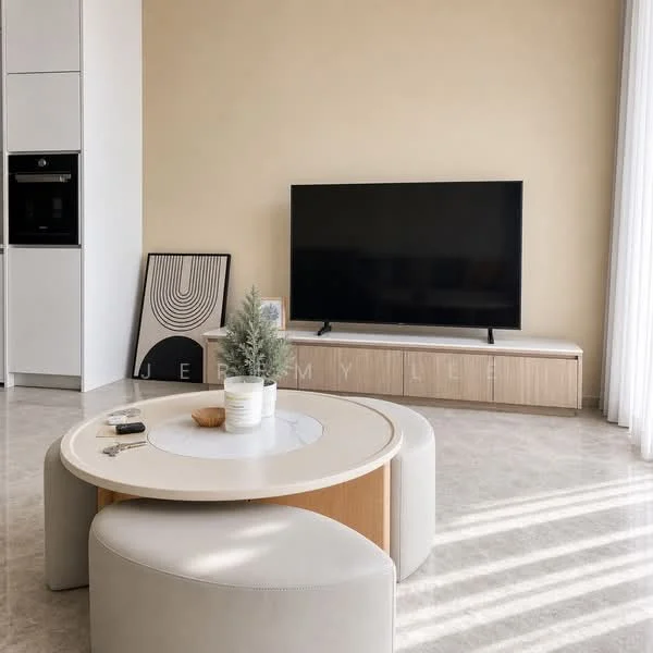 Living features: light beige painted walls, marble tile flooring, large flat-screen TV, wooden TV console, round coffee table with white top, two circular upholstered stools, framed abstract artwork, decorative potted plant, natural light from large windows with sheer curtains; style: modern.