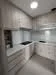 Kitchen features: light wood cabinetry, white quartz countertop, ceramic tile backsplash, built-in stove, built-in oven, single-bowl stainless-steel sink, chrome pull-down faucet, recessed downlights, neutral wall color, light-colored flooring; style: modern.