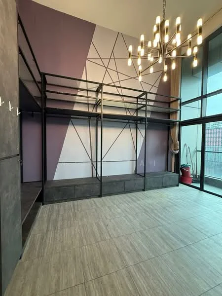 Room features: exposed metal frame structure, geometric patterned accent wall in purple and white, large floor-to-ceiling windows, chandelier with multiple bulbs, light-colored tile flooring, open space layout, high ceiling, minimalist design; style: modern; view: city.