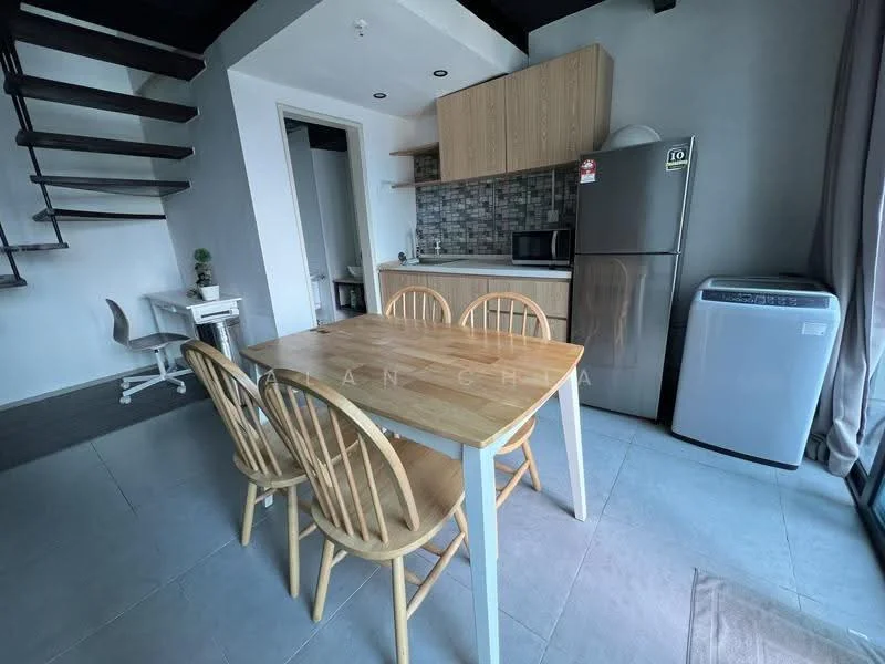 Dining features: 4-seater wooden dining table, light wood dining chairs, grey tiled flooring, white walls, kitchenette with wooden cabinetry, stainless-steel fridge, built-in microwave, grey backsplash, countertop with sink, window with sheer curtains, spiral staircase leading to upper level, small study desk with chair; style: modern.