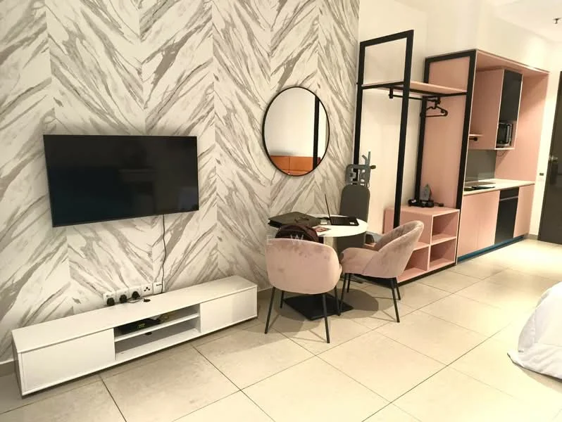 Living features: chevron patterned accent wall in light grey and white, flat-screen TV mounted on wall, white TV console with storage, round mirror above table, small round dining table, two upholstered dining chairs in light pink, open shelving unit with black frame, kitchenette area with built-in cabinets, microwave visible, tile flooring in light beige; style: modern.