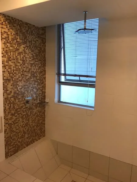 Bathroom features: mosaic tile wall, white tiled walls, shower area with rain shower head, window with blinds, built-in shower bench, tile flooring, chrome wall-mounted faucet, glass shower enclosure; style: modern.