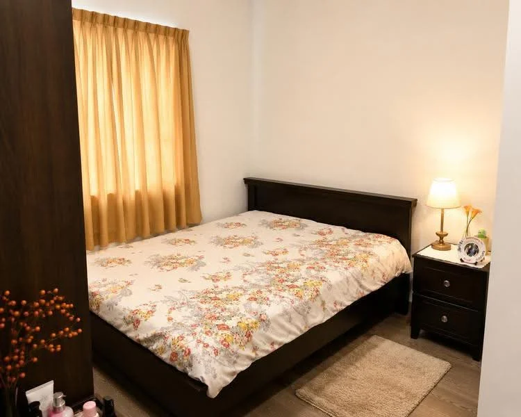 Bedroom features: queen-size bed with floral bedding, wooden bed frame, nightstand with lamp, table lamp, window with sheer curtains, light brown area rug, wooden flooring, decorative wall art, floral decor on nightstand; style: modern.