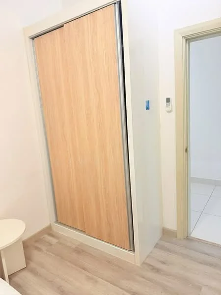 Room features: sliding wardrobe with wooden doors, light-colored walls, light wood flooring, white baseboards, doorway leading to another room, wall-mounted light switch; style: modern.