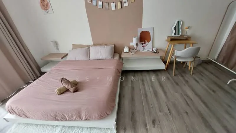 Bedroom features: queen-size bed with pink bedding, light wood platform bed frame, wooden flooring, wall-mounted bedside lamp, decorative wall art, study desk with chair, table lamp, curtains, decorative items on desk, neutral wall color, minimalist decor; style: modern.