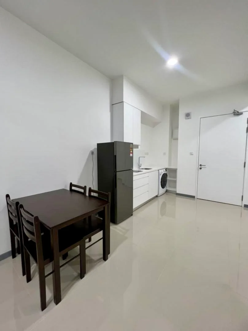 Kitchen features: white cabinets, black refrigerator, built-in oven, washing machine, white countertop, stainless-steel sink, single-bowl stainless-steel sink, 4-burner gas hob, dining table with 4 chairs, ceramic tile flooring, recessed downlights, white painted walls; style: modern.