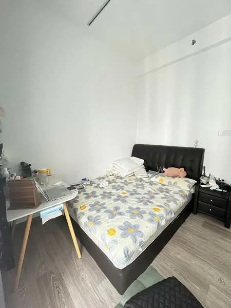 Bedroom features: queen-size bed with black upholstered headboard, bedding with floral pattern, wooden bedside table, black nightstand, laptop on the bedside table, white walls, wooden flooring, decorative items on the nightstand, piles of pillows on the bed, stuffed animal on the bed; style: modern.