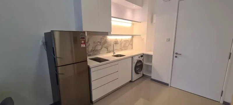 Kitchen features: white cabinetry, marble backsplash, stainless-steel fridge, single-bowl stainless-steel sink, chrome pull-down faucet, built-in washing machine, countertop with under-cabinet lighting, ceramic tile flooring; style: modern.