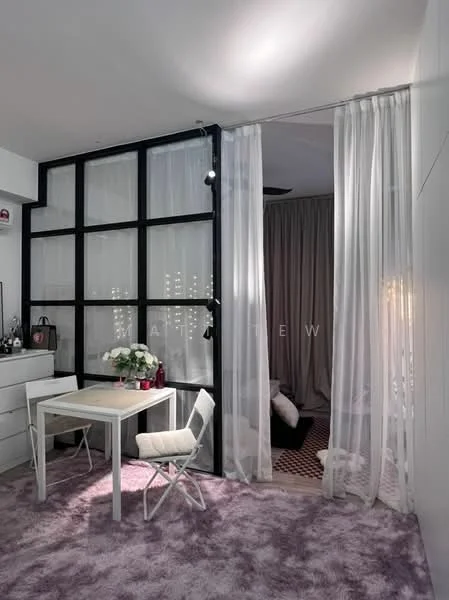 Room features: light purple carpet flooring, white walls, black framed glass partition, sheer white curtains, folding white table, white folding chair, decorative flowers on table, dark curtain in background, ambient ceiling lighting; style: modern.