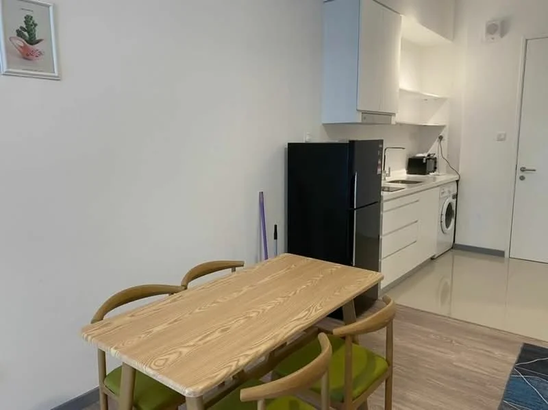 Kitchen features: white cabinetry, black refrigerator, built-in oven, stainless-steel sink, chrome pull-down faucet, washing machine, ceramic tile flooring, dining table with wooden surface, 4 wooden chairs with green upholstery, wall-mounted cabinets, countertop space, light-colored walls, recessed lighting; style: modern.