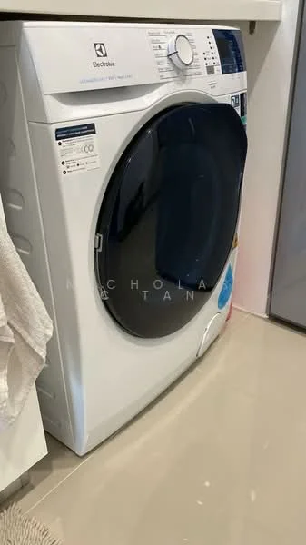 Laundry features: front-load washing machine in white, control panel with digital display, chrome door handle, detergent dispenser, smooth surface flooring, white cabinetry, towel hanging on side, visible plumbing connections; style: modern.