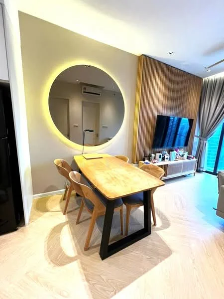 Dining features: wooden dining table with black legs, 4 wooden dining chairs, large round mirror with backlighting, wall-mounted TV, wood panel accent wall, light-colored wooden flooring, air conditioning unit on wall, decorative items on TV console; style: modern.
