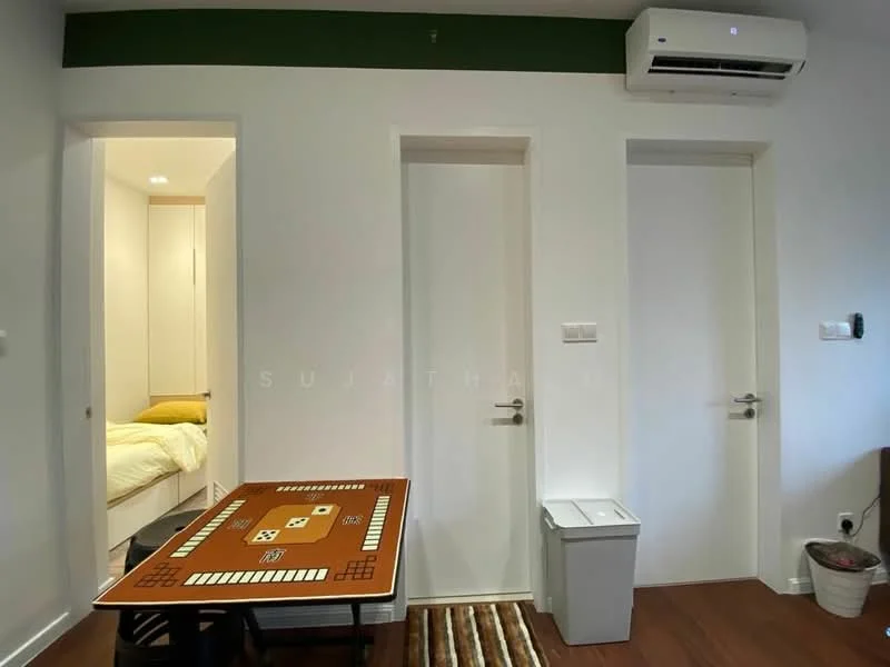 Room features: white painted walls, wooden flooring, 1 wall-mounted split AC, 2 white doors, small white trash bin, brown area rug, wooden table with game board design; style: modern.