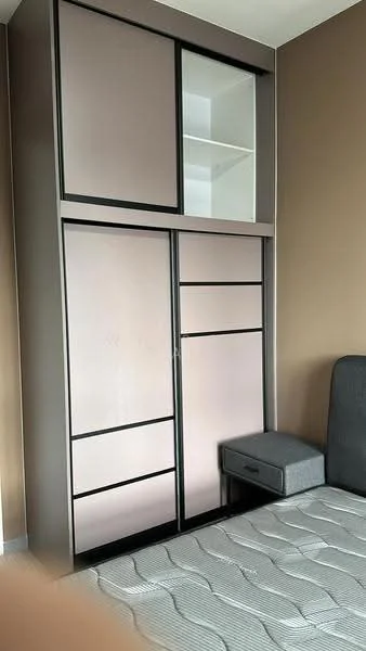 Bedroom features: built-in wardrobe with sliding doors, grey and black cabinetry, open shelving above wardrobe, bedside table with drawer, queen-size bed, neutral wall colour, textured bedding, carpeted flooring; style: modern.