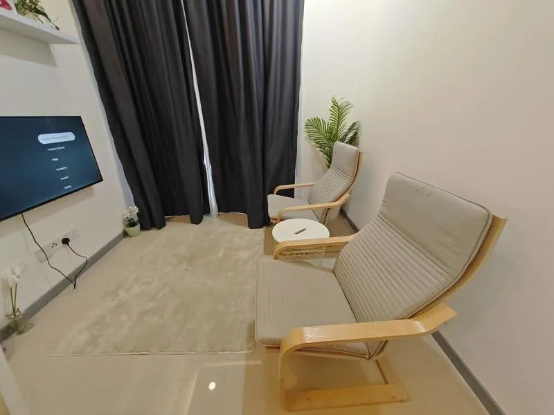 Living features: two wooden armchairs with grey cushions, small round side table, light beige area rug, floor-to-ceiling curtains in black, wall-mounted TV, white painted walls, ceramic tile flooring, indoor plant; style: modern.