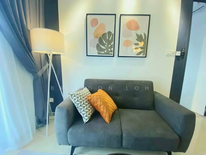 Living features: grey fabric sofa, two decorative cushions in orange and black-and-white patterns, floor lamp with white shade, framed artwork with abstract designs, light grey walls, curtains in dark grey, neutral flooring, wall-mounted light switches; style: modern.