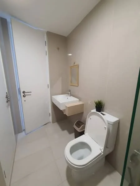 Bathroom features: white wall tiles, light beige wall, single-sink vanity with wood cabinet, chrome basin mixer, framed mirror, one-piece toilet, tile flooring, small potted plant, waste bin; style: modern.
