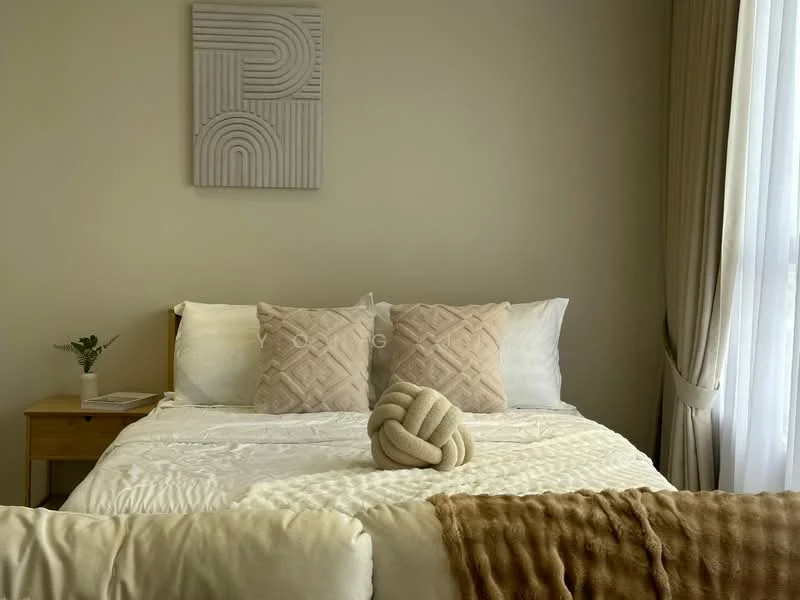 Bedroom features: king-size bed, white bedding, two decorative pillows with geometric pattern, knotted decorative throw, wooden bedside table, small potted plant on bedside table, framed wall art, floor-to-ceiling window with sheer curtains; style: modern.