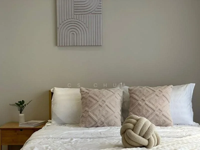 Bedroom features: queen-size bed with white bedding, two decorative pillows with geometric patterns, knot-shaped decorative pillow, wooden bedside table, small potted plant on bedside table, textured wall art above the bed, neutral wall color, lampshade on bedside table; style: modern.