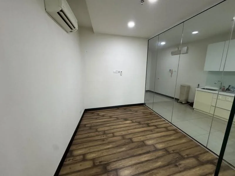Room features: white painted walls, wooden flooring, 1 wall-mounted split AC, glass partition, recessed downlights, kitchenette with cabinets, tile flooring in kitchenette area, countertop in kitchenette; style: modern.