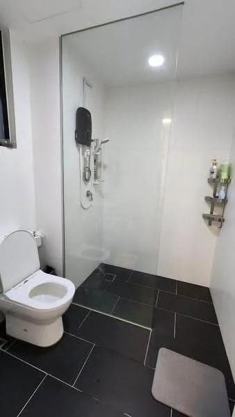 Bathroom features: walk-in shower with glass enclosure, rain shower head, handheld shower, white toilet, black tile flooring, white tiled walls, recessed downlights, shower caddy with toiletries, sliding window, bath mat; style: modern.