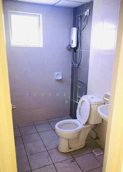 Bathroom features: white toilet, wall-mounted shower head, grey tiled walls, light grey tiled flooring, small window for natural light, toilet paper holder, shower mixer, exposed plumbing, corner drain.