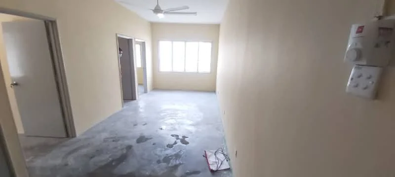 Room features: light beige painted walls, concrete flooring, 5-blade ceiling fan, large windows with multiple panes, doorway leading to another room, doorway leading to bathroom, visible electrical panel, natural light from windows.