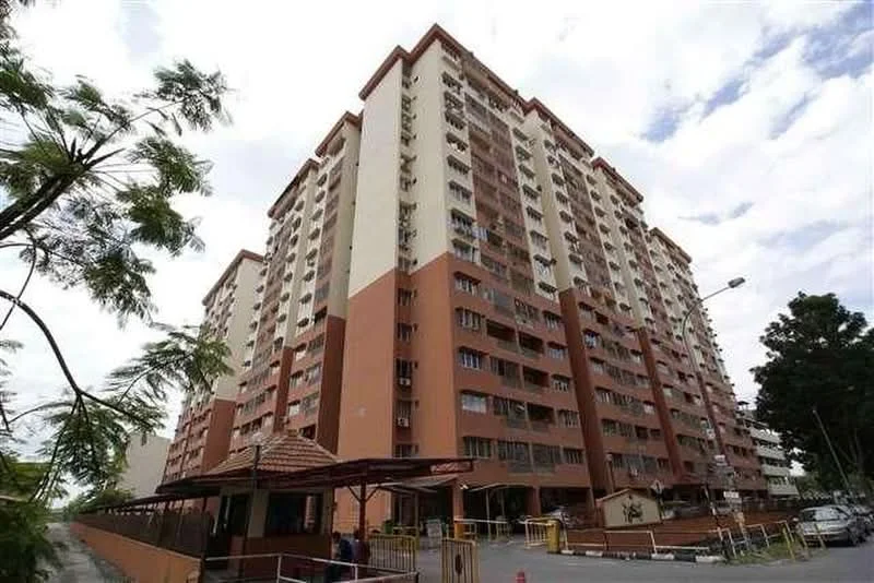 Exterior type: mid-rise condominium; features: cream painted facade, brown accent panels, multiple balconies, windows with grilles, gated entrance, covered entrance with awning, landscaped area in front, surrounded by trees, parking area visible, security booth at entrance; style: modern.