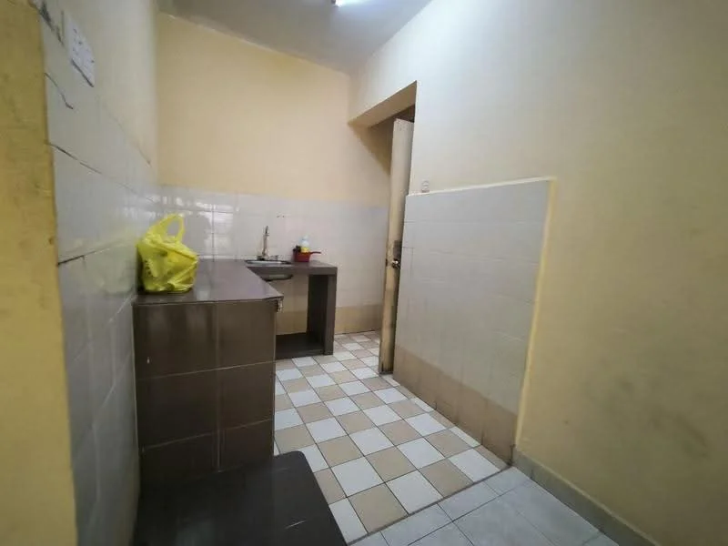 Kitchen features: yellow painted walls, white tiled backsplash, grey laminate countertop, single-bowl stainless-steel sink, wall-mounted faucet, checkered floor tiles, wooden door, open layout, cabinets under countertop, window for natural light.